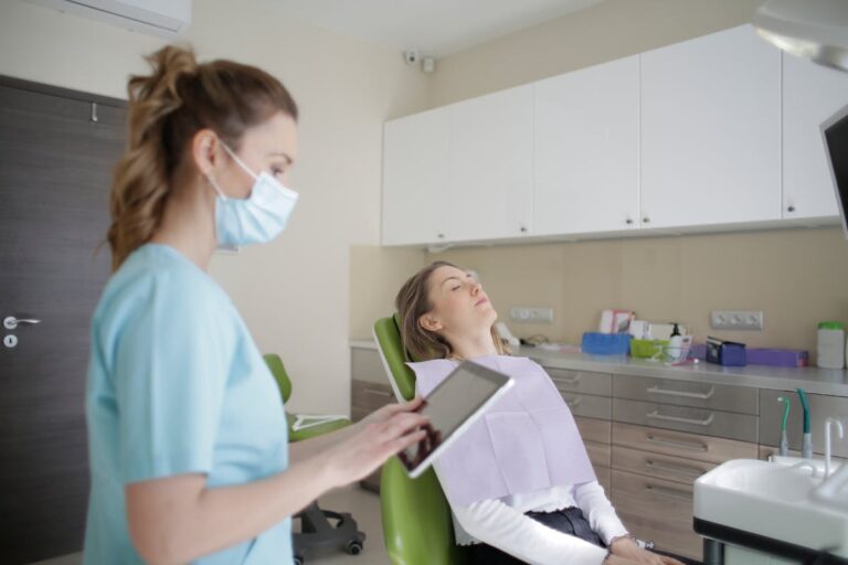 Female orthodontist using tablet while assisting patient in clinic