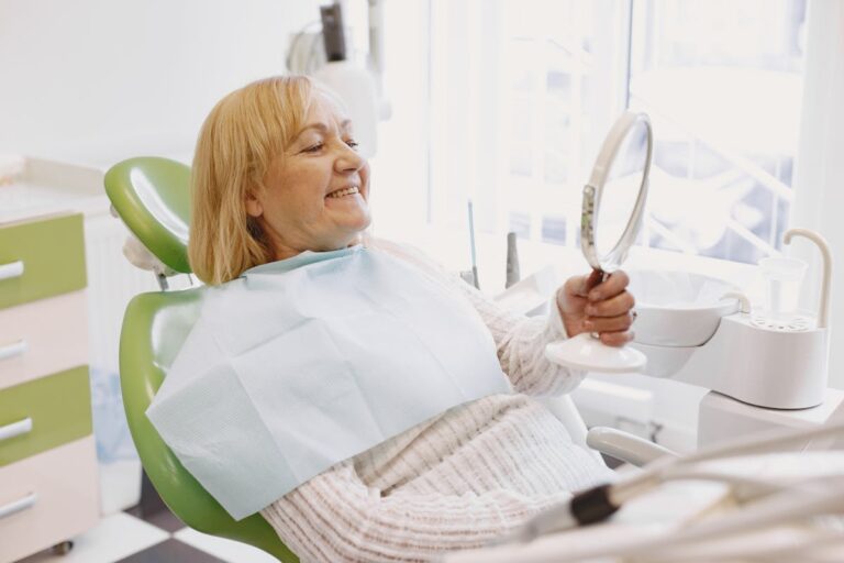 Woman Looking at Her Teeth in a Mirror in a Dentist Room
