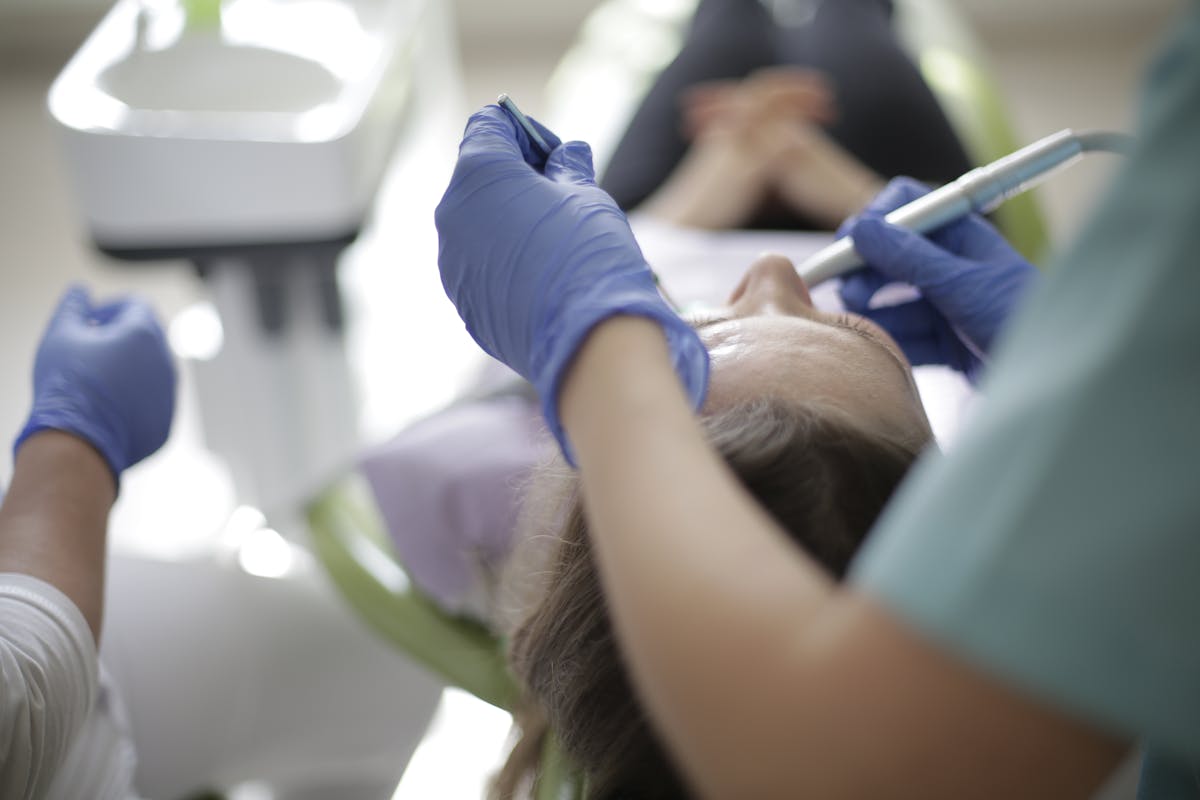 Anonymous dentist using drill and mouth mirror for dental treatment
