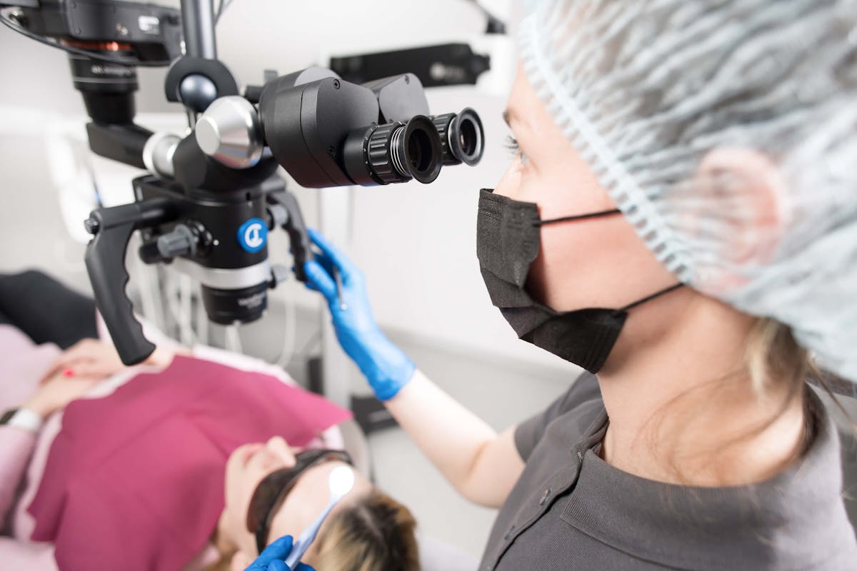 Dentist with a Microscope Treating a Patient