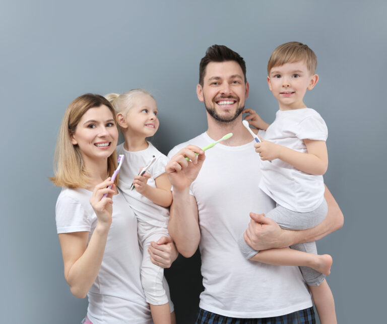 Young family brushing teeth on grey background