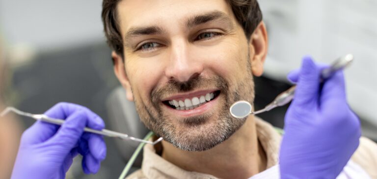 Closeup shot of dentist examining male patients teeth in dental clinic. Man having his teeth examined by female dentist