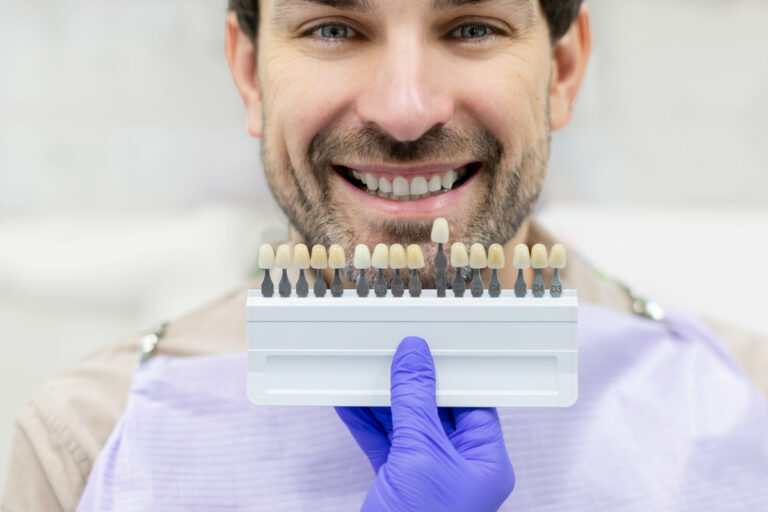 Dentist holding dental teeth shade guide chart, choosing right emanel color for male patient, closeup shot