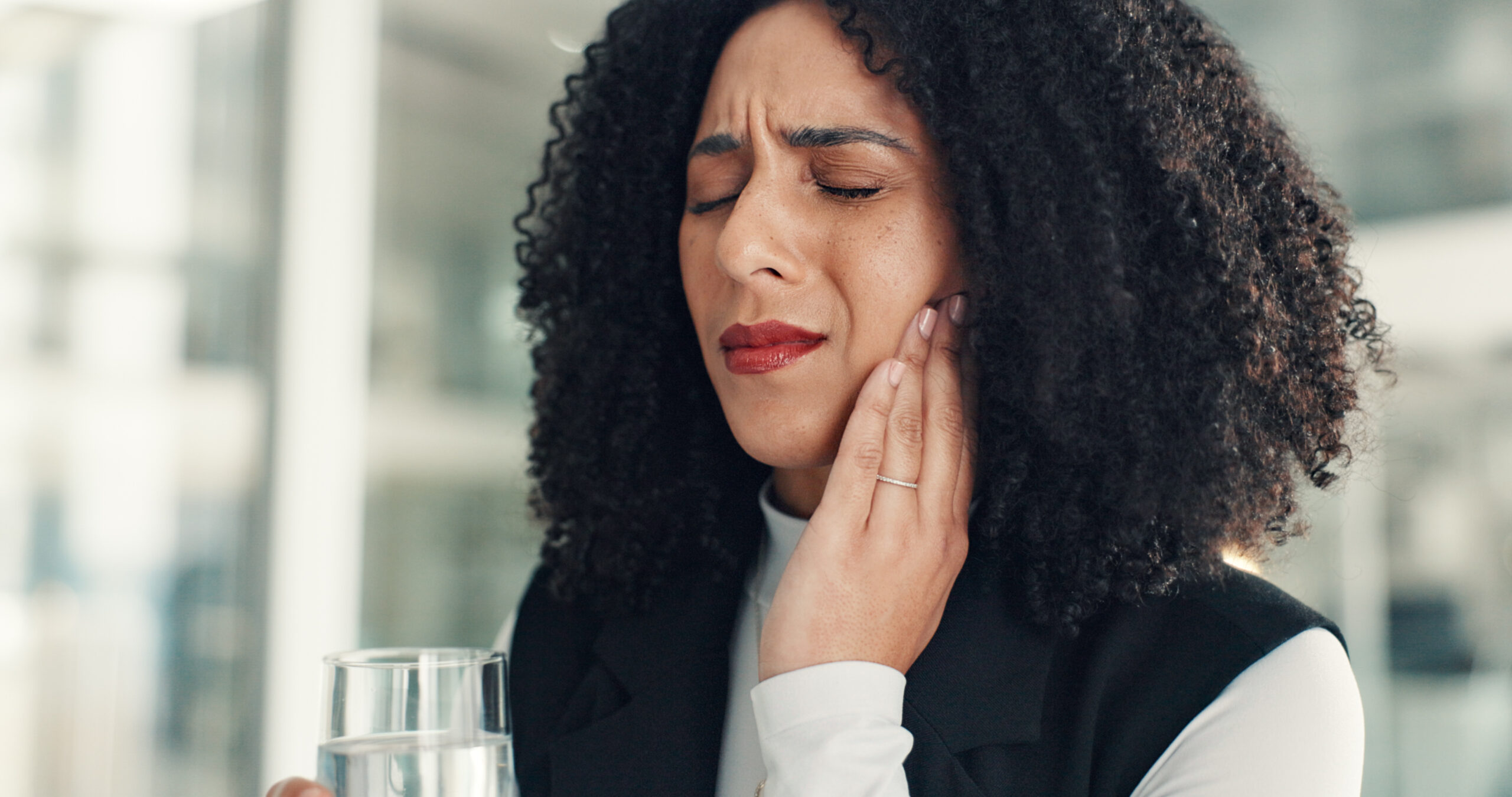 Water, business and woman in office with toothache, oral discomfort or inflammation in mouth. Cavity, gum disease and female person in workplace with tmj pain, teeth sensitivity and dental injury