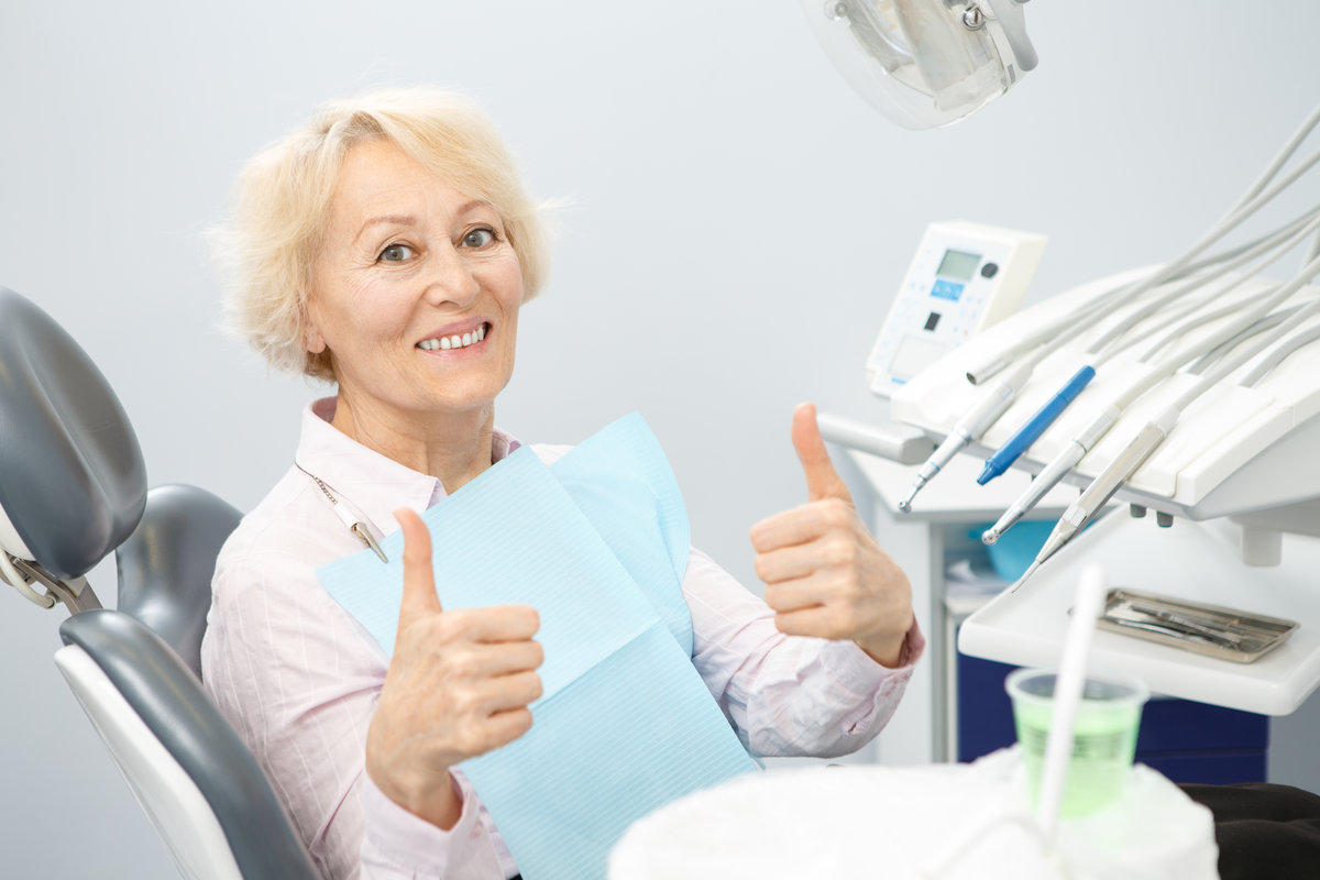 Happy elderly woman smiling showing thumbs up sitting at the dentist office after dental examination copyspace happiness client patient service healthy healthcare medicine insurance trust satisfaction